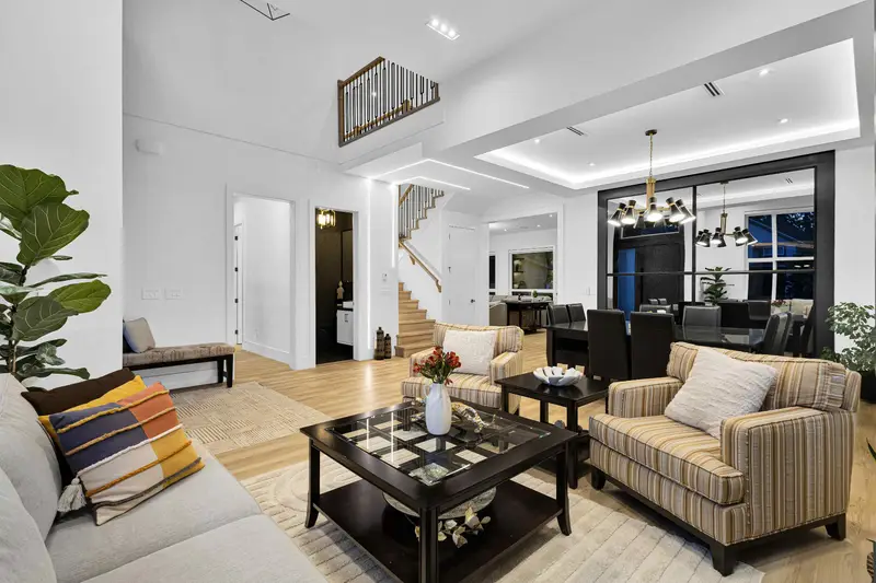 Open living room with double-height ceiling and staircase in Langley luxury home