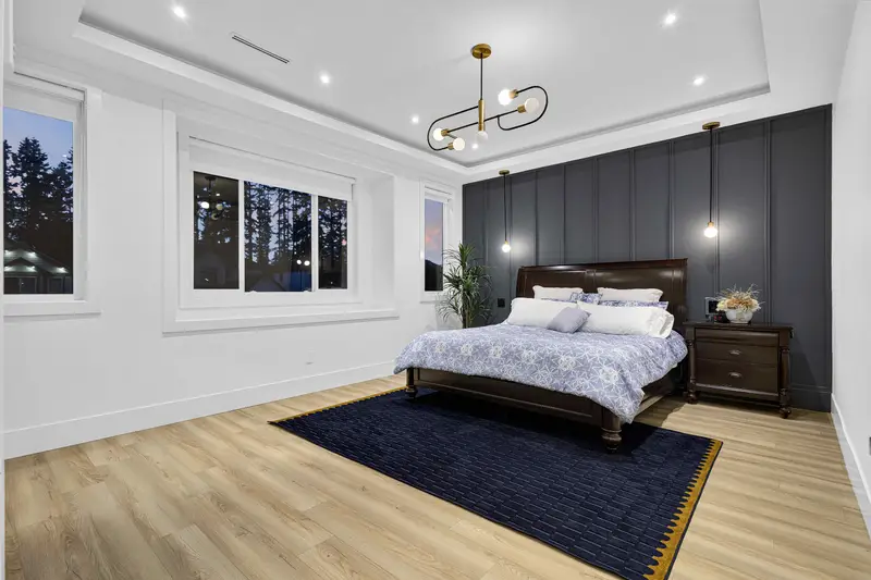 Primary bedroom with dark panel feature wall and twilight window views