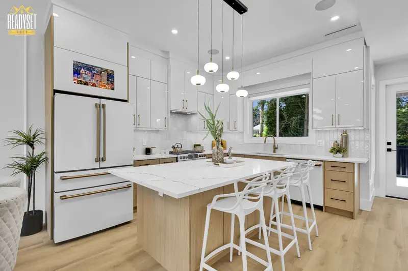 Modern white kitchen with quartz island and pendant lighting at 7143 W Brewster Street