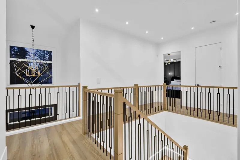 Upper landing with designer chandelier and modern wood railing in Langley home