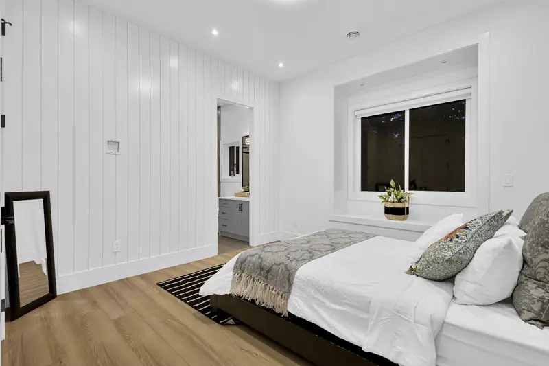 Bright bedroom with white shiplap accent wall and ensuite access