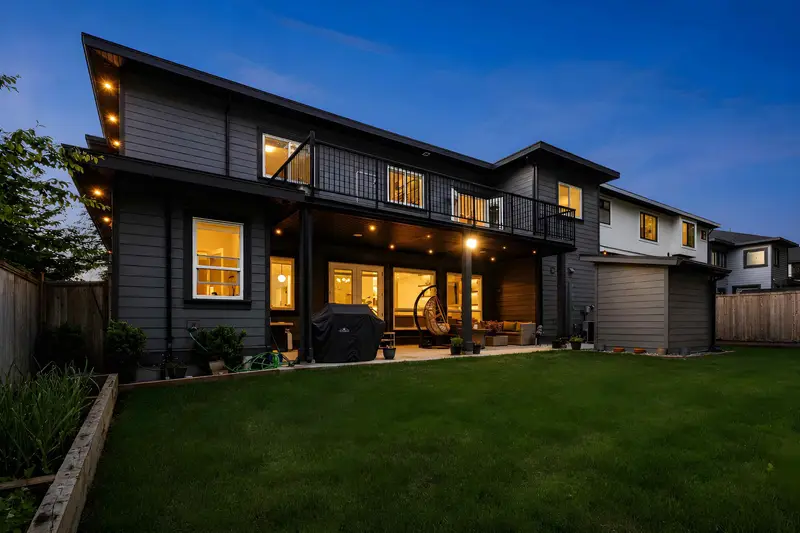 Rear exterior with covered patio and lit upper deck on a Langley home