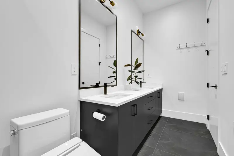 Modern bathroom with double vanity, black cabinetry and gold fixtures