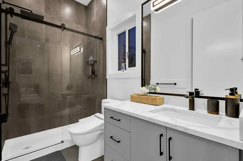 Modern bathroom with walk-in glass shower and marble vanity in Langley home