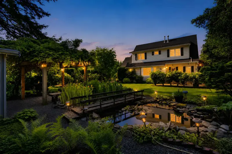 Twilight backyard view with illuminated pond and pergola at 23430 50 Avenue Langley