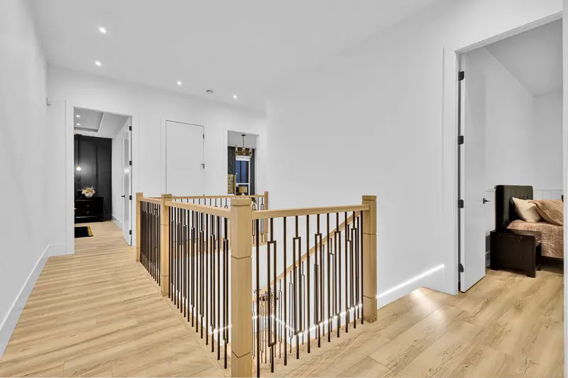 Bright upper hallway with wood floors and modern railing in luxury Langley home